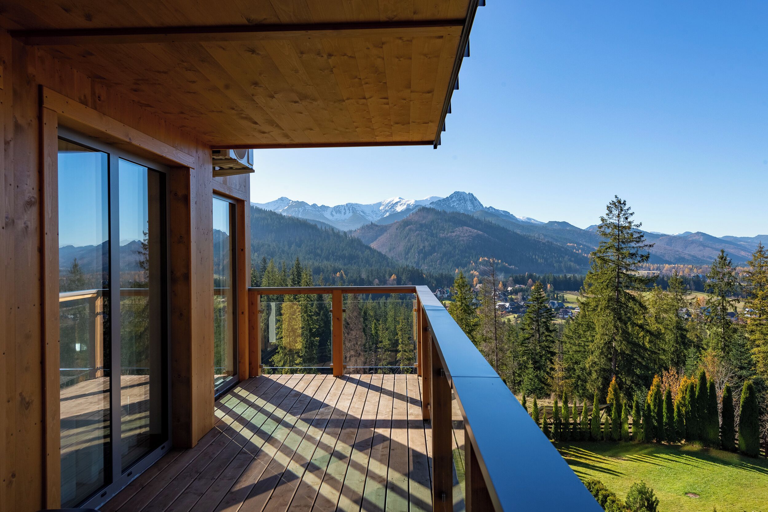 A wooden deck with large windows overlooking a mountainous landscape.