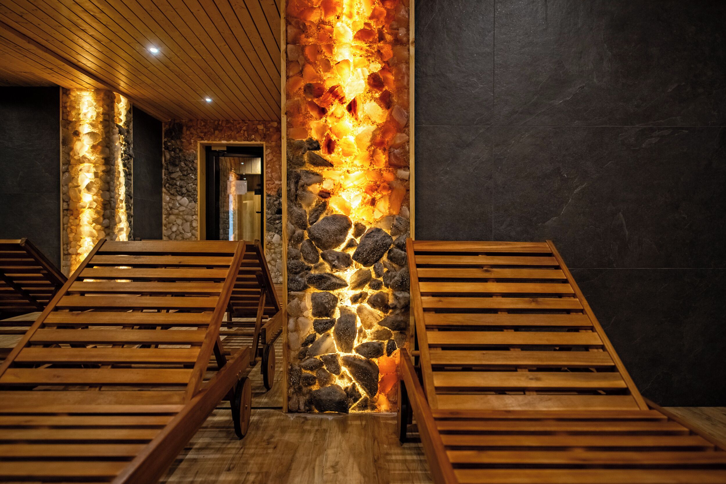 A spa area with wooden loungers and a stone pillar with embedded lighting.