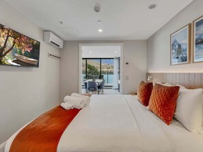 A hotel room with a bed, a view through a door, and a dining area visible in the background. - Lake Wakatipu Stay | Close to Town (Queenstown)