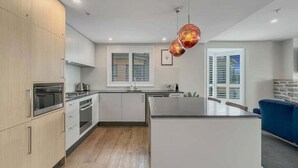 Cozinha moderna com armários de madeira, eletrodomésticos de aço inoxidável e uma ilha central.