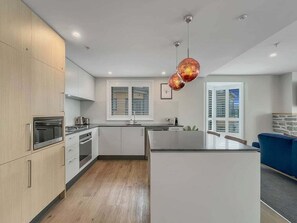 Eine moderne Küche mit Holzschränken, Edelstahlgeräten und einer zentralen Kochinsel.