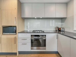 A modern kitchen with stainless steel appliances, wooden cabinets, and a sleek countertop. - Lake Wakatipu Stay | Close to Town (Queenstown)