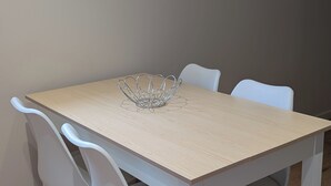 A dining table with a metal centerpiece, white chairs, and a framed artwork on the wall. - Cozy 2-room apartment with a whirlpool tub (Vaugneray)