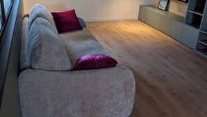 A modern living room with a grey sofa, a red cushion, and a wooden floor. - Cozy 2-room apartment with a whirlpool tub (Vaugneray)