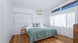A bedroom with a bed, bedside table, and a window with curtains. - Luxury Waterfront Stay at Tallebudgera Creek (Gold Coast)