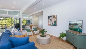 A modern living room with a large sofa, chairs, a coffee table, and artwork on the wall. - Luxury Waterfront Stay at Tallebudgera Creek (Gold Coast)