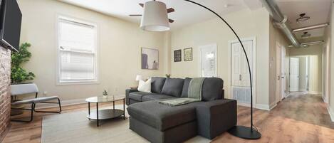 A modern living room with a sectional sofa, a round coffee table, and a large floor lamp.