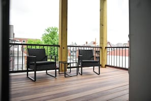 A balcony with two chairs and a small table, wooden flooring, and a metal railing. - Perfect for Families, 3BR Home Near CMU, Pitt & UPMC (Pittsburgh)