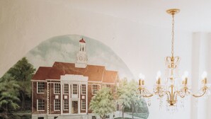 Un mural que muestra un edificio con una torre de reloj, una araña y una escalera de balaustres blancos.