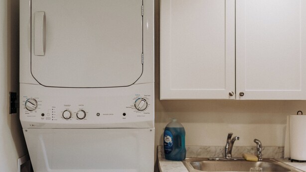 Cocina compacta con lavadora blanca, un lavamanos y armarios.