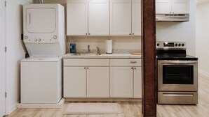 Una cocina compacta con muebles blancos, horno integrado y lavadora.
