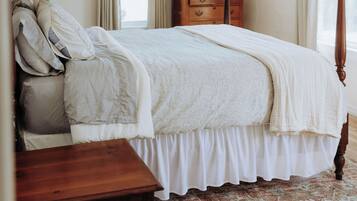 Une chambre à coucher avec un lit à baldaquin, une commode en bois, un miroir et un tapis à motifs.