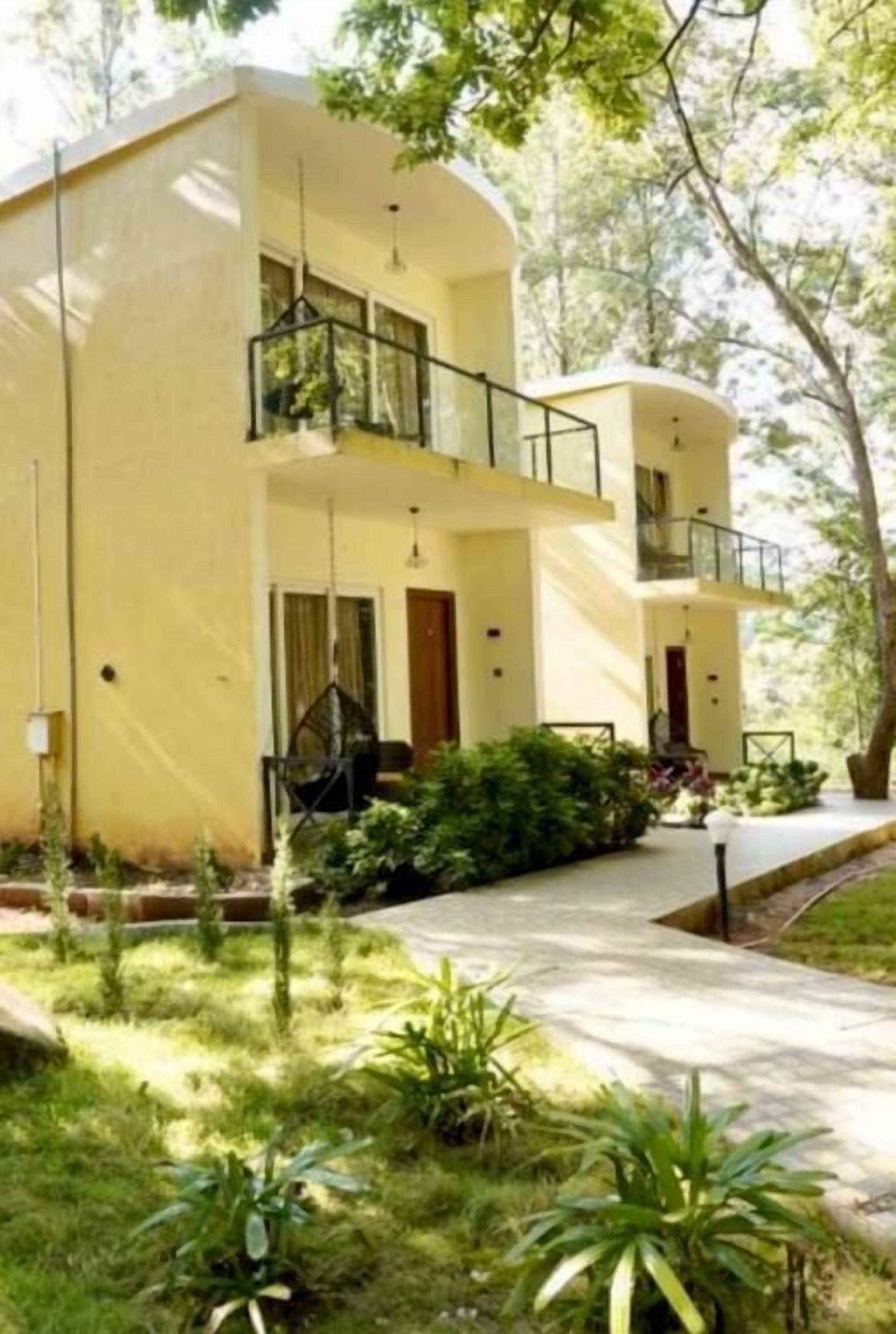 A two-story building with a balcony on the upper floor, surrounded by greenery.