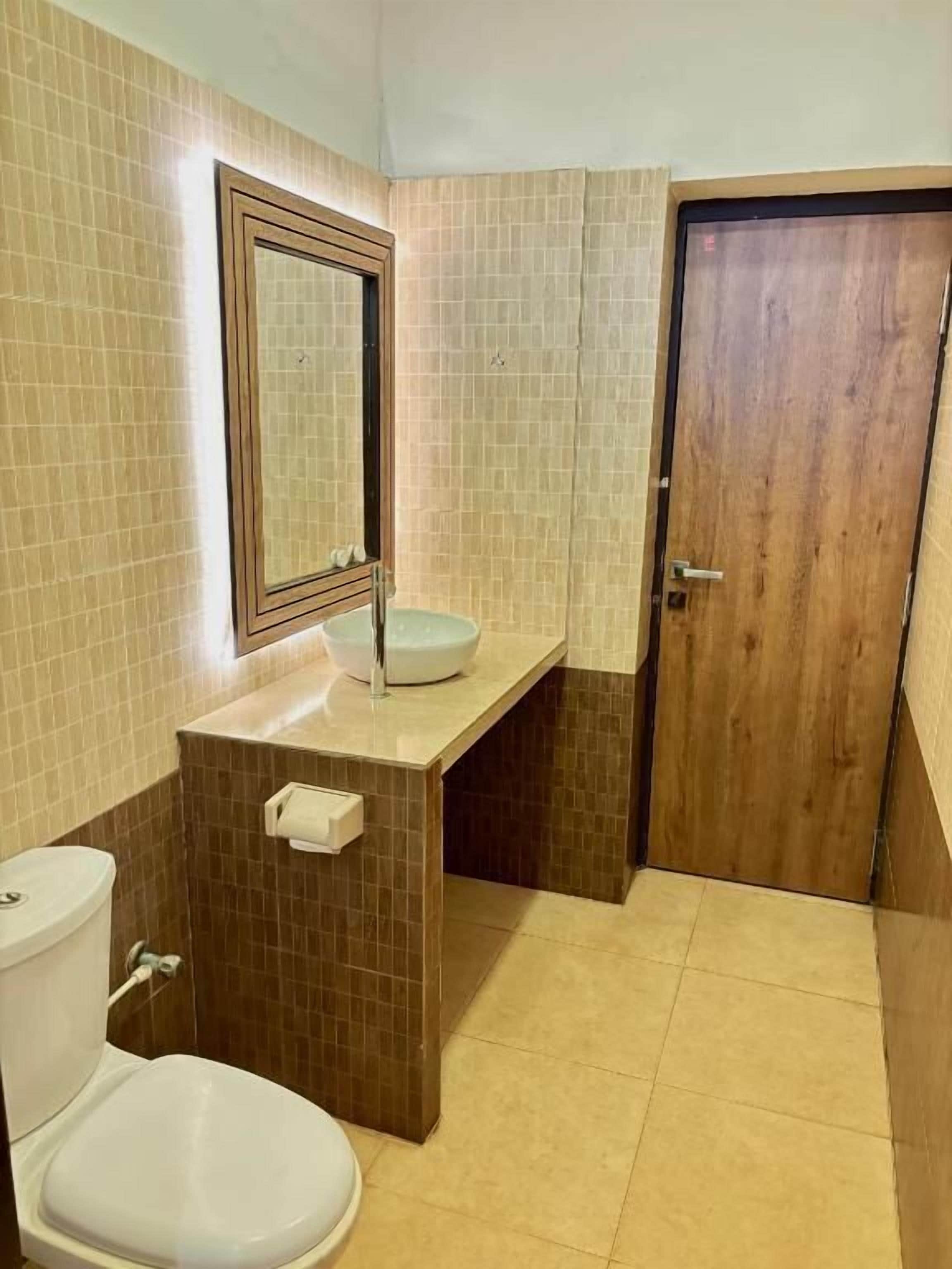 A bathroom with a toilet, sink, and mirror.