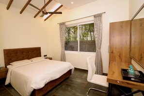 A bedroom with a bed, a desk, a chair, a window with curtains, and a ceiling fan.