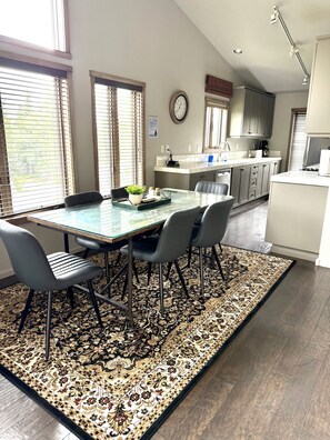 Una cocina moderna con comedor, que incluye una isla grande, piso de madera oscura y una alfombra estampada.
