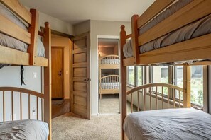Una habitación con literas, una puerta de madera y vistas por una ventana.