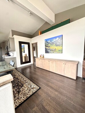 A modern kitchen with dark wood flooring, a dining area with a patterned rug, and a large painting on the wall. - New Listing 3 BR condo in Mammoth Lakes. Snowcreek V. Perfect for your getaway. (Mammoth Lakes)