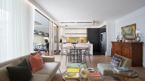 A modern living room with a sofa, coffee table, and chairs, a dining area with a table and chairs, and a kitchen with cabinets and appliances. - Alexandra Breeze, Camperdown (Camperdown)