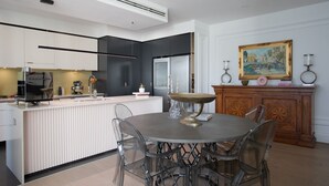 A modern kitchen with a central island, white cabinetry, and a dining area with a round table and chairs. - Alexandra Breeze, Camperdown (Camperdown)