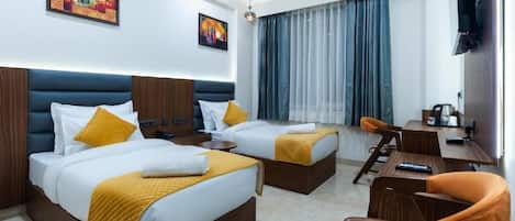 A hotel room with two beds, a desk, a chair, and a TV.