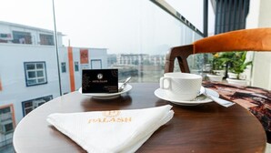Hotelkamer met een ontbijt gedekte tafel, stadszicht en een bord met de naam van het hotel.