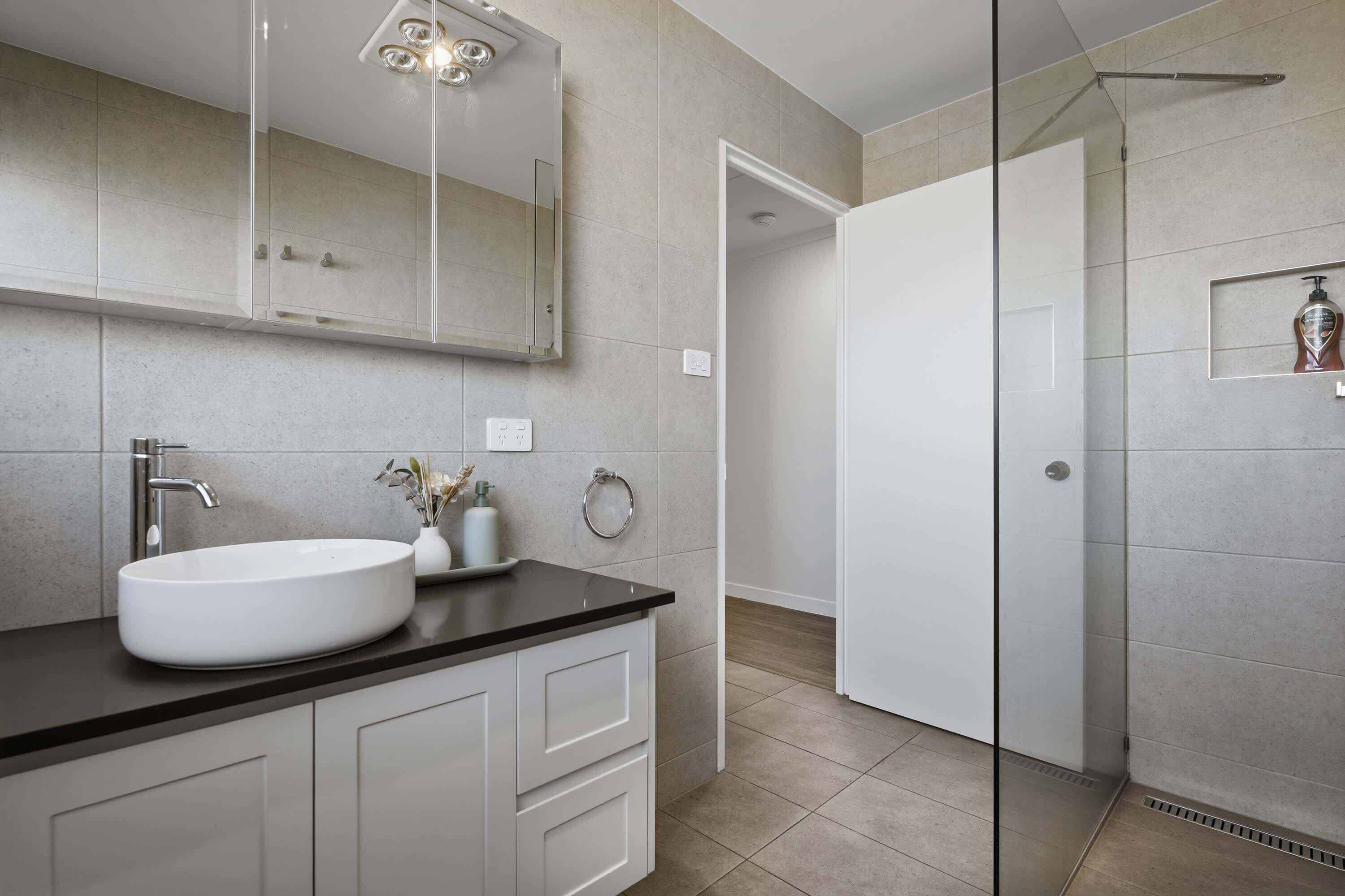 A modern bathroom with a large white sink, a mirror above it, and a shower area with a glass door.