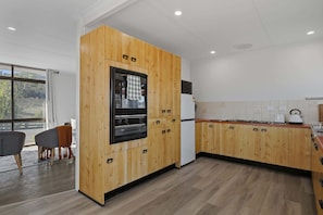 A modern kitchen with wooden cabinetry, a built-in oven, and a refrigerator.