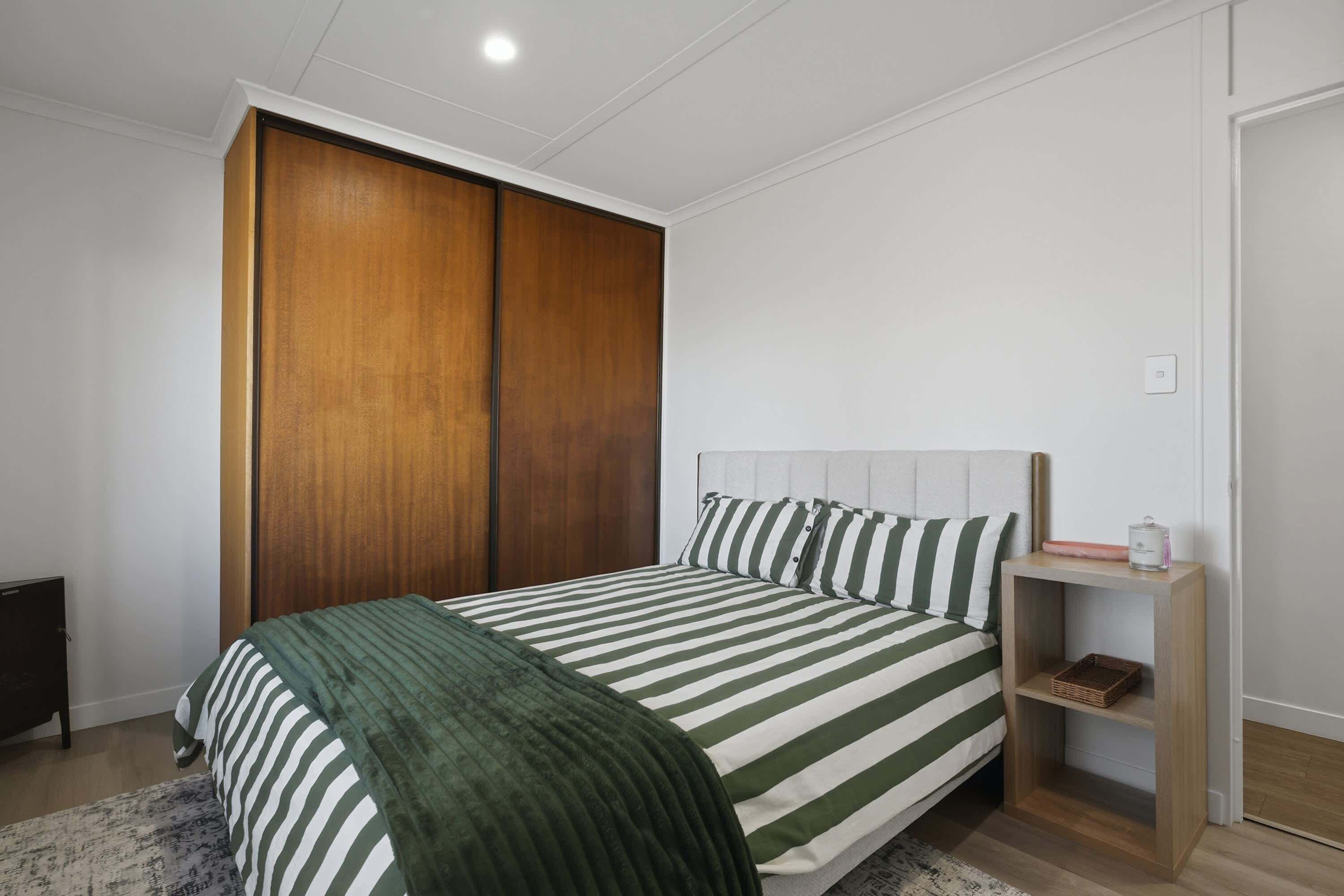 Une chambre à coucher comprenant un lit, une armoire, une table de chevet et une commode.