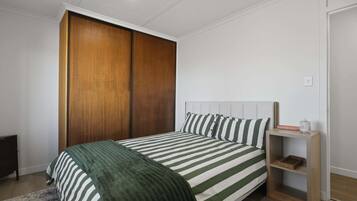 Une chambre à coucher comprenant un lit, une armoire, une table de chevet et une commode.
