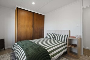 A bedroom with a bed, a wardrobe, a bedside table, and a nightstand.