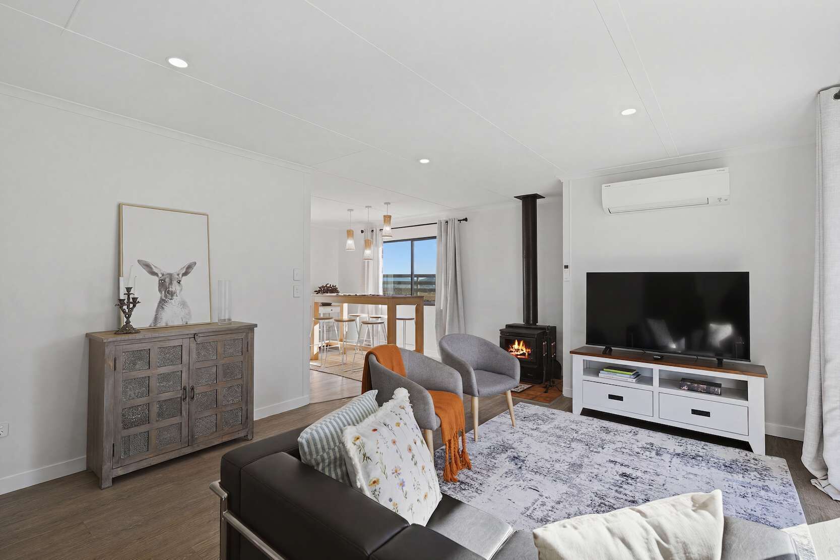 A modern living room with a sofa, TV, fireplace, and a dining area with a view.