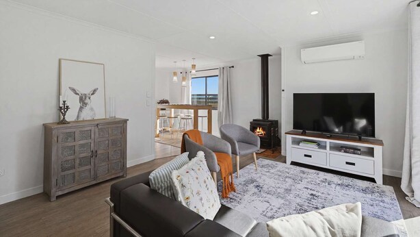 En moderne stue med sofa, fjernsyn, pejs og spiseområde med udsigt.