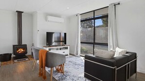 En moderne stue med pejs, sofa, fjernsyn og et stort vindue.