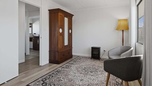 En moderne stue med et træskab, en grå lænestol og en tæppe med et mønster.