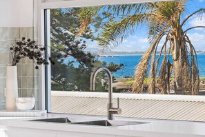 A bathroom with a large window, a sink, and a mirror.