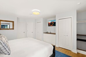 Une chambre à coucher avec un lit, une commode, un miroir et un téléviseur.