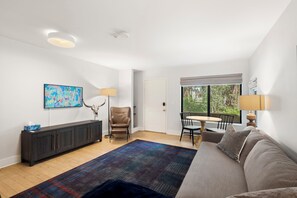 A modern living room with a sofa, a coffee table, a dining table with chairs, a lamp, a painting, and a decorative skull. - Telluride Creekside Condo | 3 Min to Chair 7 (Telluride)