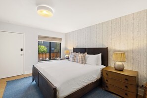 A bedroom with a large bed, bedside lamps, a nightstand, and a window with a view of the outside. - Telluride Creekside Condo | 3 Min to Chair 7 (Telluride)
