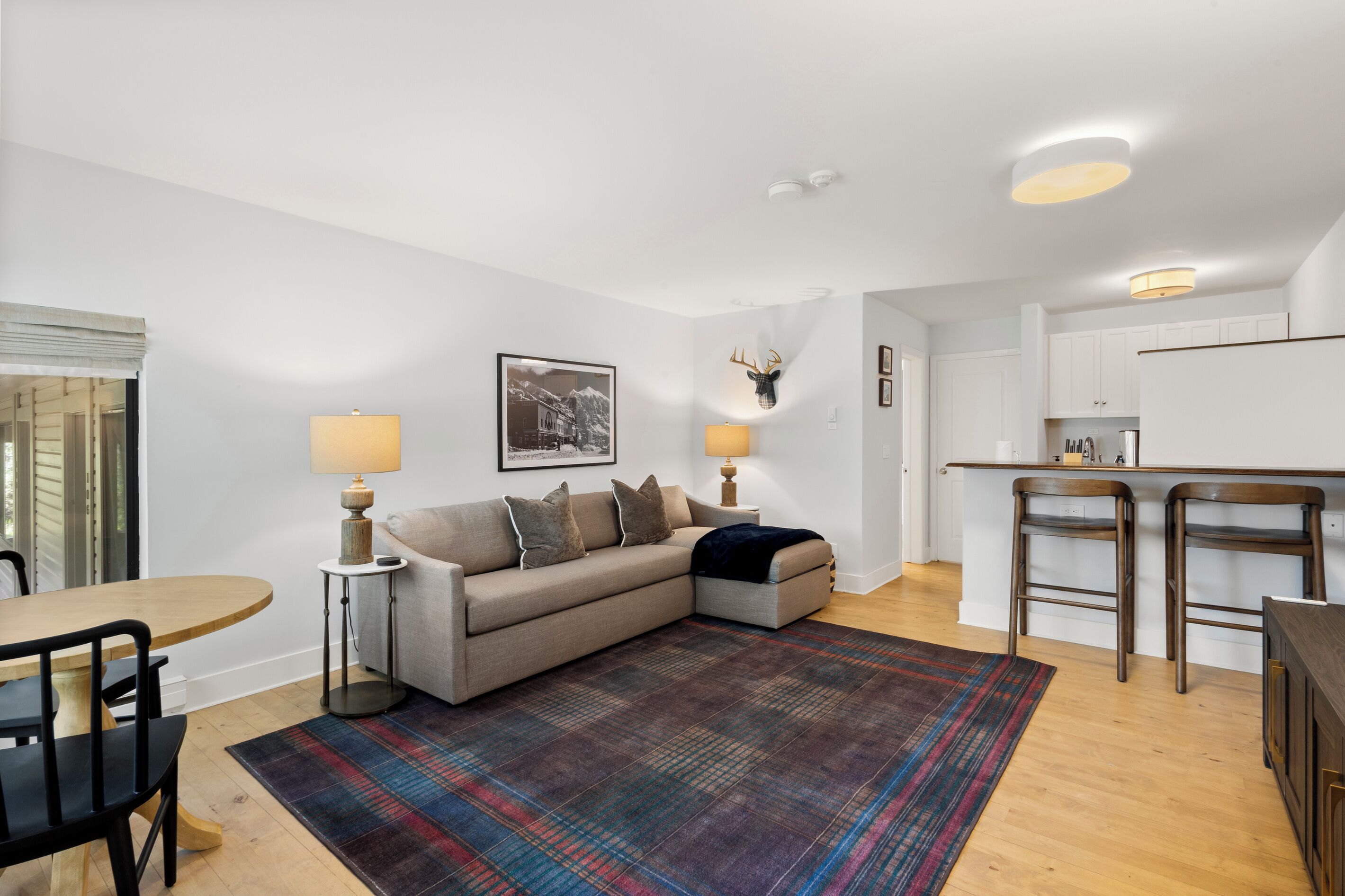 A modern living room with a sofa, a dining table, and a kitchen area.