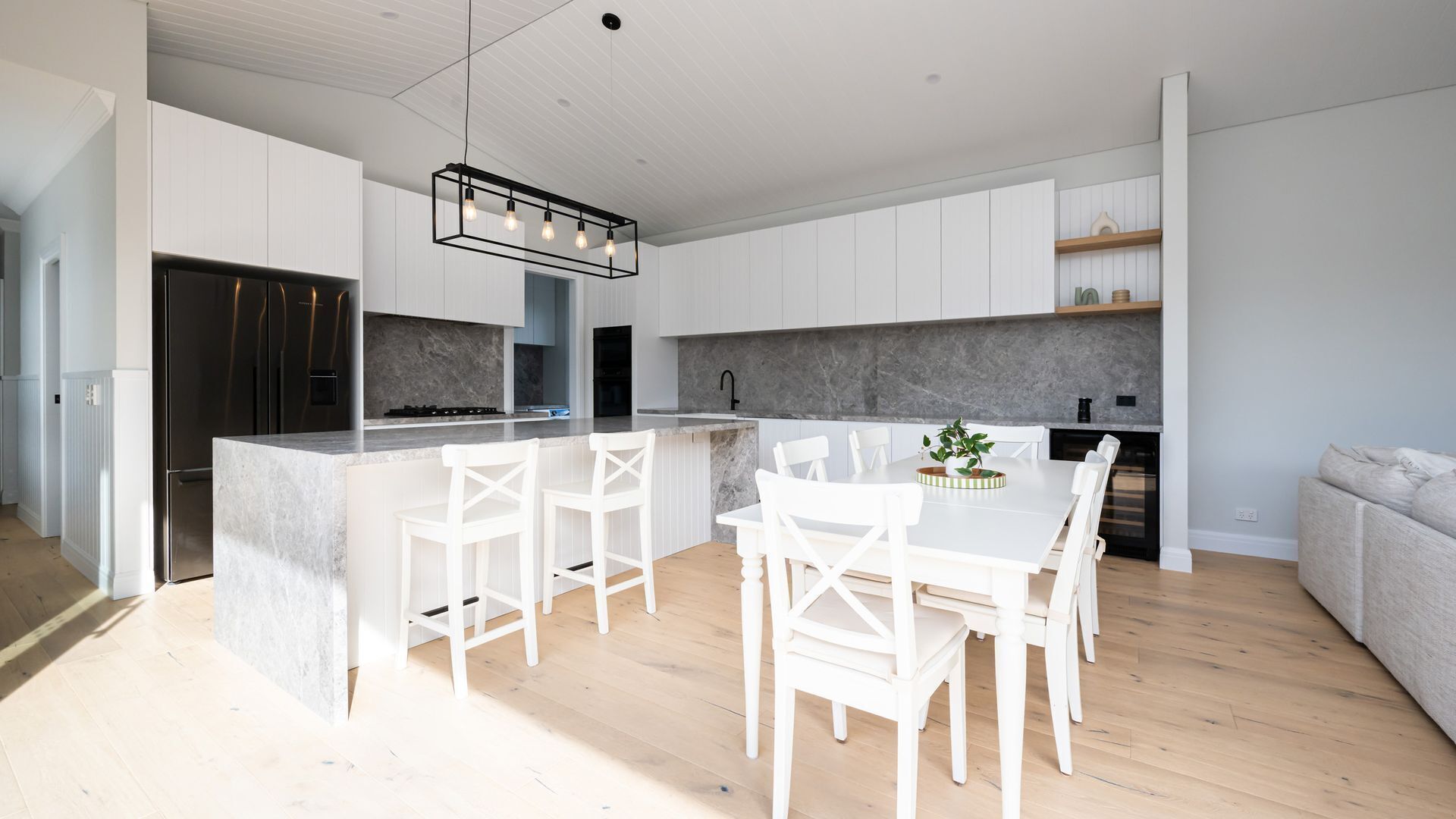 A modern kitchen with white cabinetry, a central island with seating, and a built-in oven.