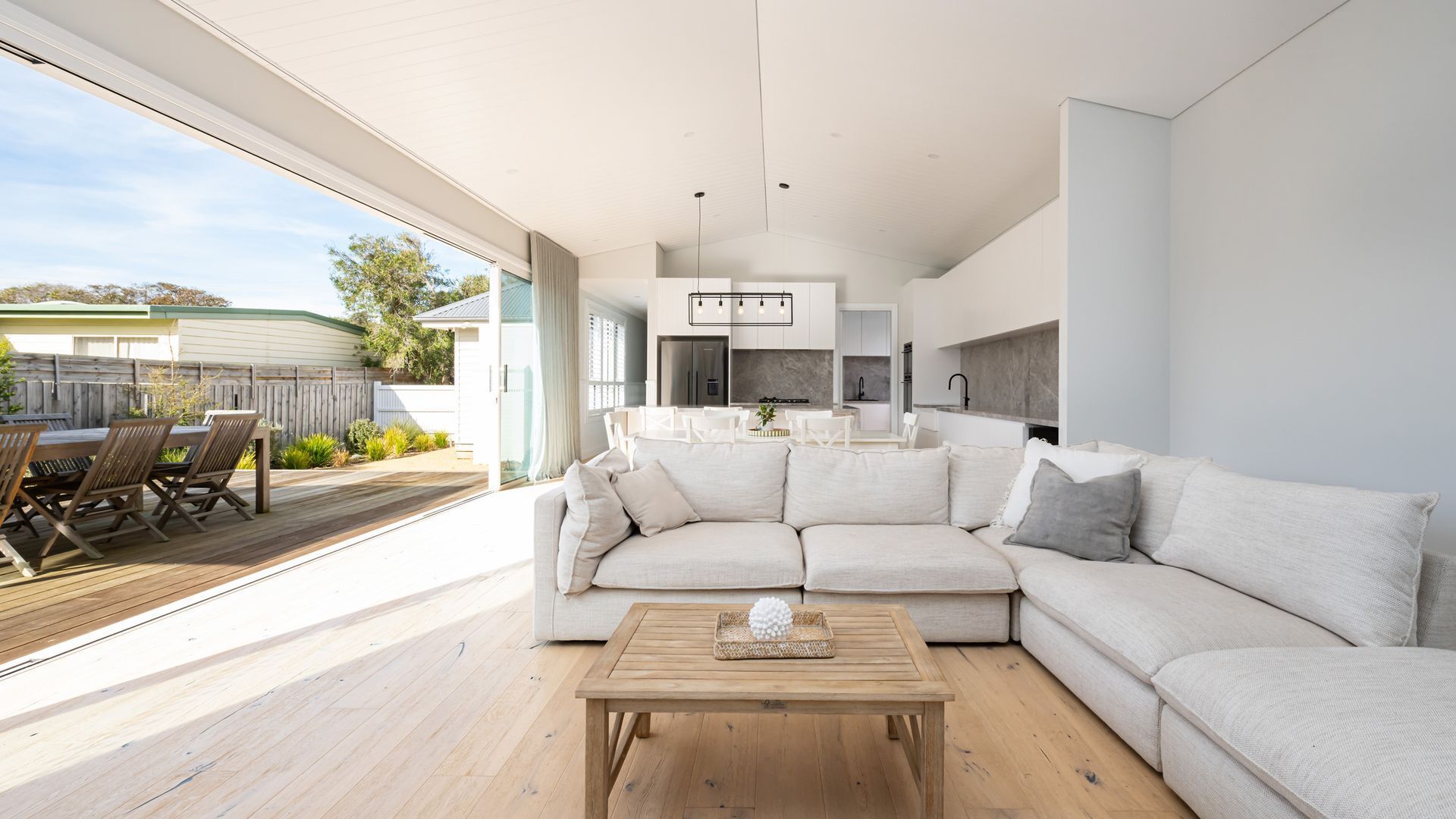 Ein modernes Wohnzimmer mit einem großen Ecksofa, einem Holztisch und Blick auf die Außenpatio-Terrasse.