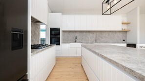 A modern kitchen with white cabinetry, a marble countertop, and a built-in oven. - Koonya Blairgowrie Luxe Retreat | Pet Friendly, Walk to Beach (Blairgowrie)