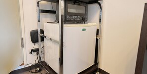 A compact kitchenette with a built-in oven, a small refrigerator, and a microwave.