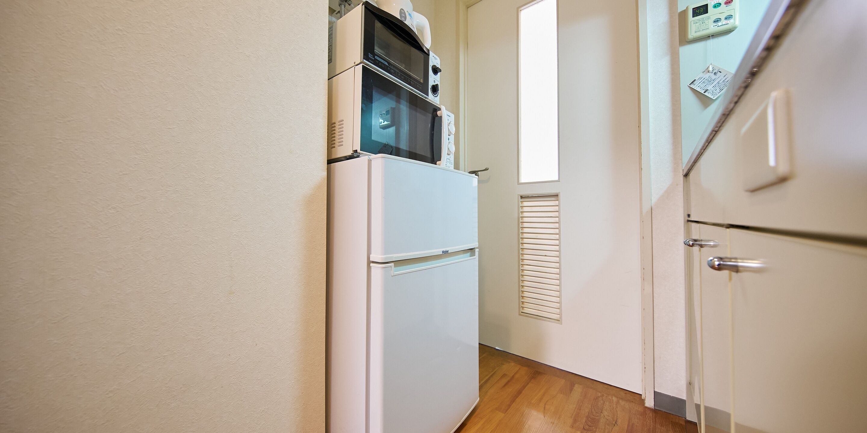 A narrow hallway with a white refrigerator and a microwave on top.