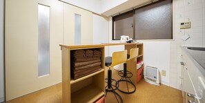 A small kitchenette with a window, a towel rack, and a kettle on the counter.