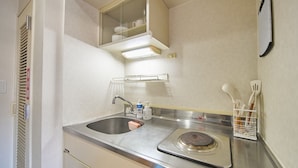 Een kleine hotelbadkamer met een wastafel, spiegel en een klein aanrecht met toiletartikelen.