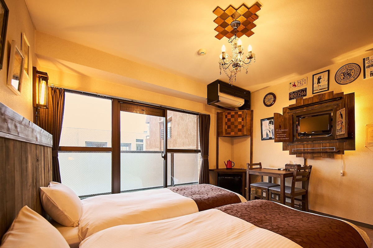 Habitació d'hotel amb dos llits, una televisió, un penjol i una finestra amb vista.