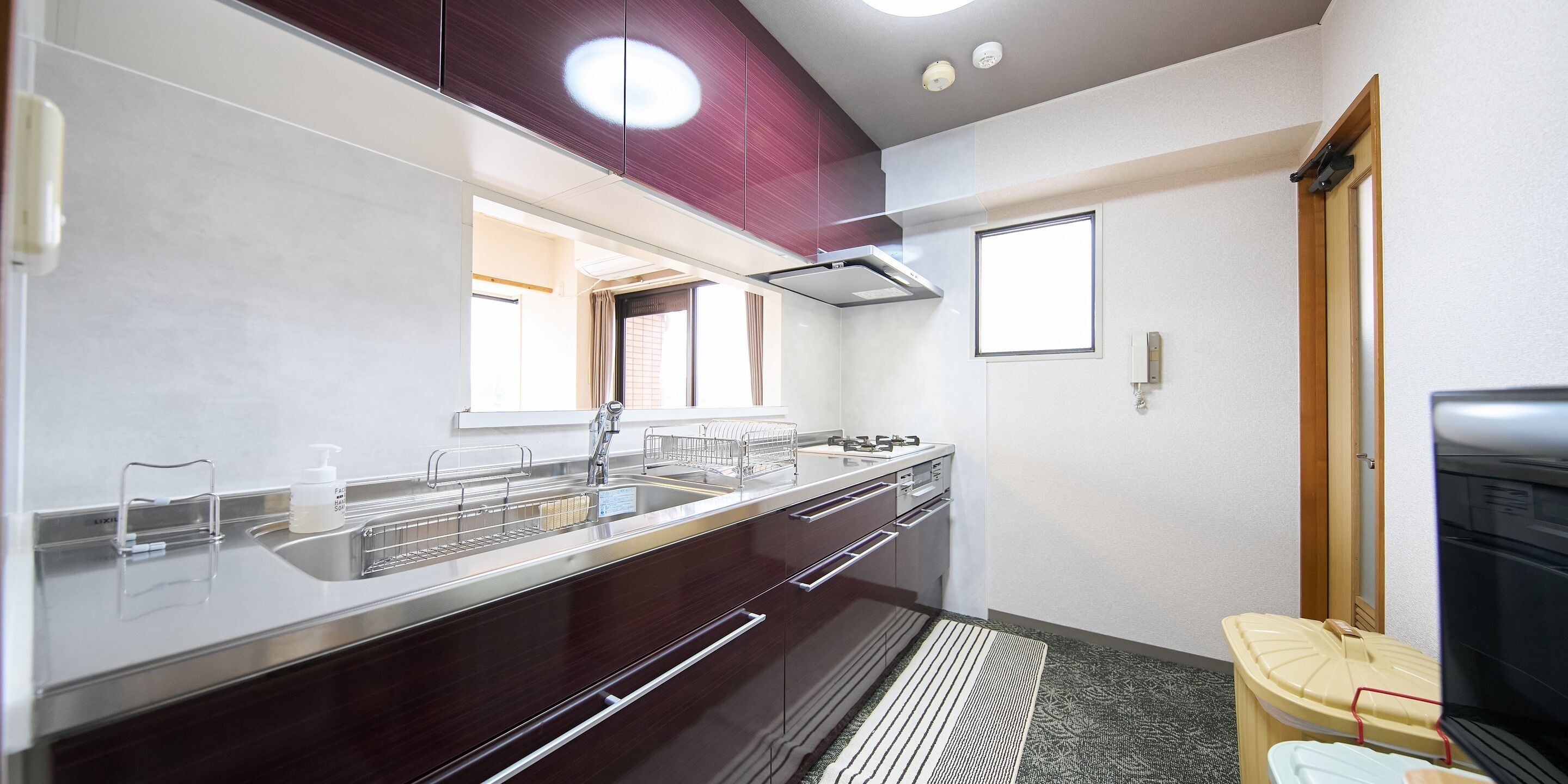 A modern kitchen with stainless steel appliances, a built-in oven, and a large window.