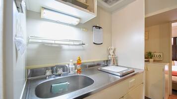 A modern bathroom with a stainless steel sink, a mirror, a towel rack, and a soap dispenser.